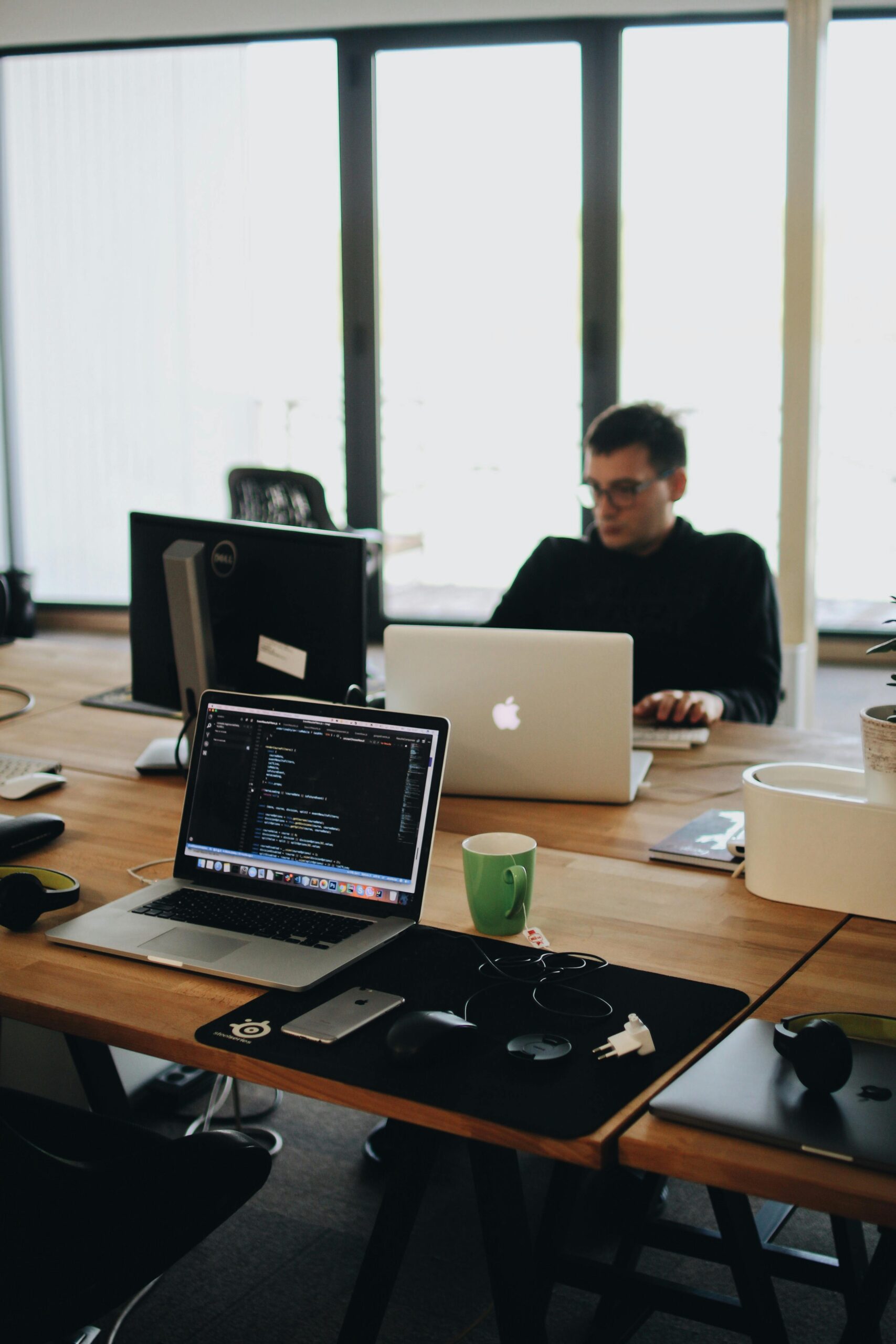 A web developer working on code in a modern office setting with multiple devices.